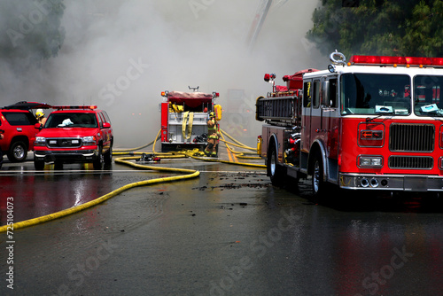 A smoke filled street with yellow fire hoses and fire engines. photo