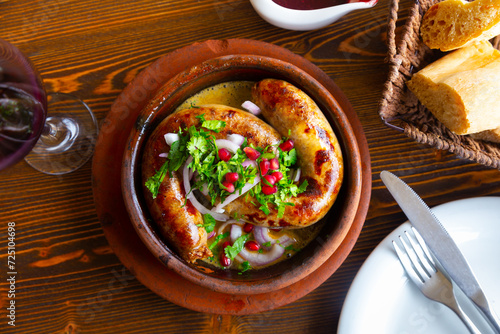 Two appetizing grilled meat sausages served with onion, herbs and pomegranate, georgian Kupaty