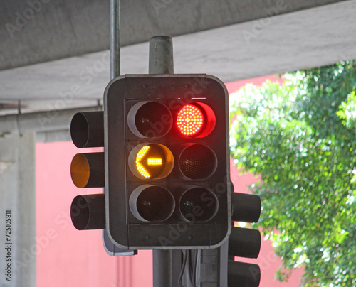 Photography Traffic lights under a freeway showing red stop light and orange arrow