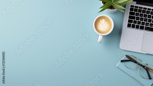 A tidy workspace with a laptop, coffee cup, and plant on a blue background photo