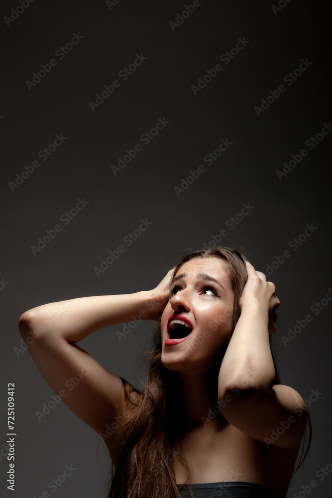 Beautiful girl studio portrait. Making hand and face gestures against dark background. Beautiful girl studio portrait. Making hand and face gestures against dark background.