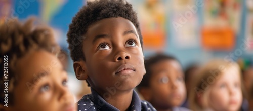 Focused black schoolboy attentively observing lesson in diverse primary classroom.