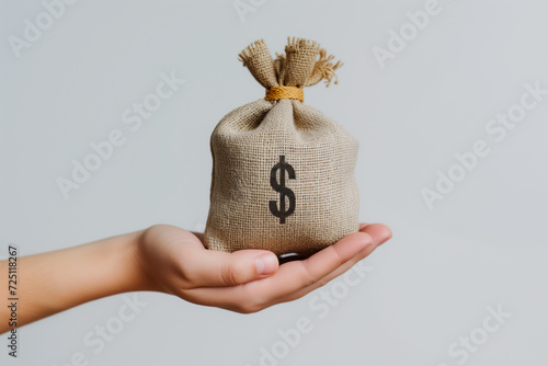 Hand holding a small burlap money bag with a dollar sign