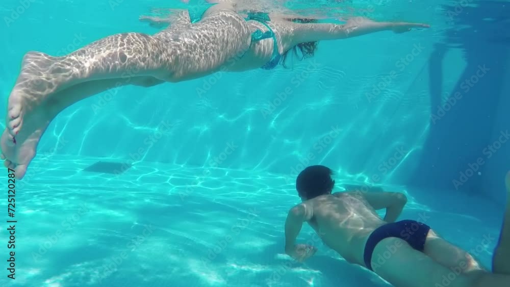 Man in smelting swim under lying woman underwater in pool. Man in smelting swim under lying woman underwater in pool.