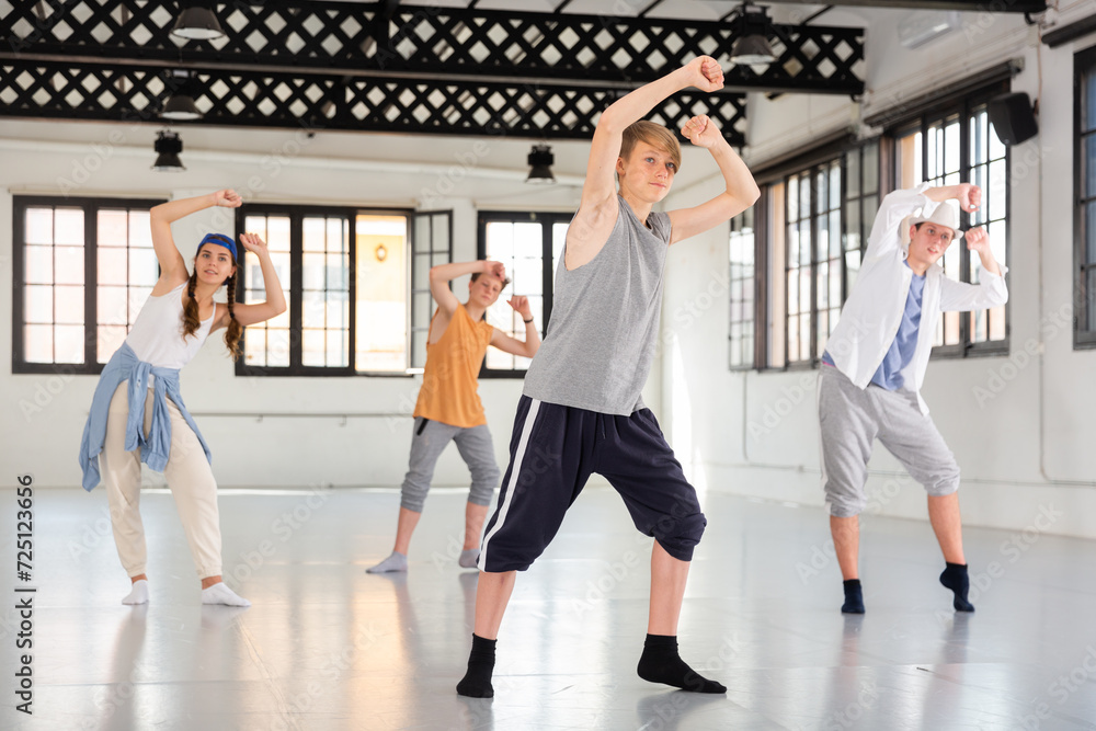 Teenage girl and boys having dance training in studio, performing hip hop elements
