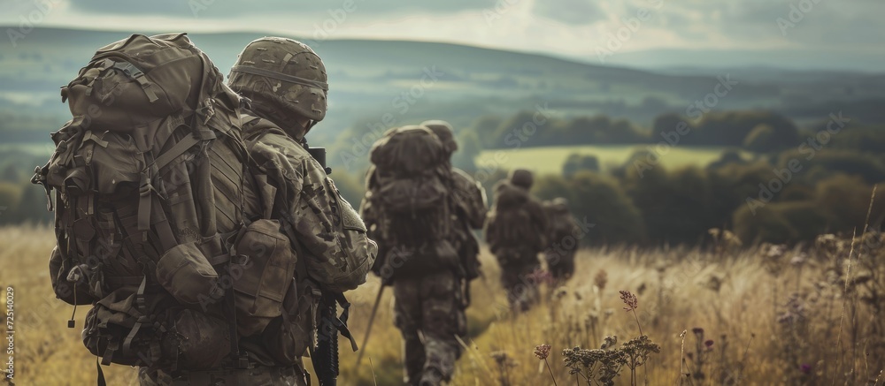 British army soldiers, both male and female, tabbing across Wiltshire's open countryside carrying 25Kg bergens.