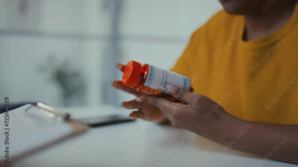 Medium tilting shot of young African American female patient sitting in clinic, talking to GP, holding bottle with prescription drug, reading instructions on label, asking about negative side effects Medium tilting shot of young African American female patient sitting in clinic, talking to GP, holding bottle with prescription drug, reading instructions on label, asking about negative side effects