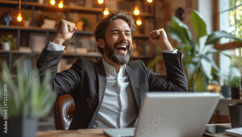 Businessman working in the office and raising his hands in joy
