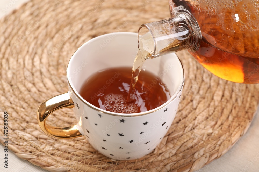 Pouring aromatic tea into cup at table, closeup Pouring aromatic tea into cup at table, closeup