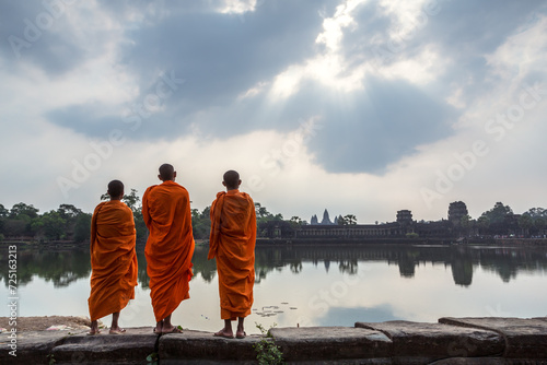 Three buddhist monks in front of Angkor Wat temple and lake, Siem Reap, Cambodia photo