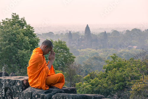 Buddhist monk meditating with Angkor wat temple in the background, Cambodia photo