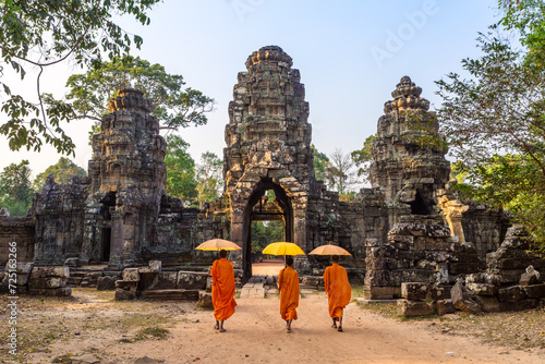 Three buddhist monks with umbrella walking to the old temple ruins, Angkor wat, Cambodia