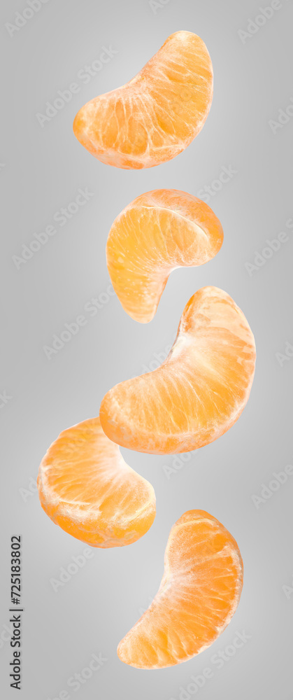 Pieces of fresh ripe tangerine falling on grey background Pieces of fresh ripe tangerine falling on grey background