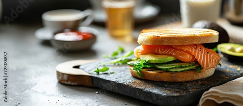 Breakfast menu in a modern coffee house, salmon and avocado sandwich on a grey table. photo