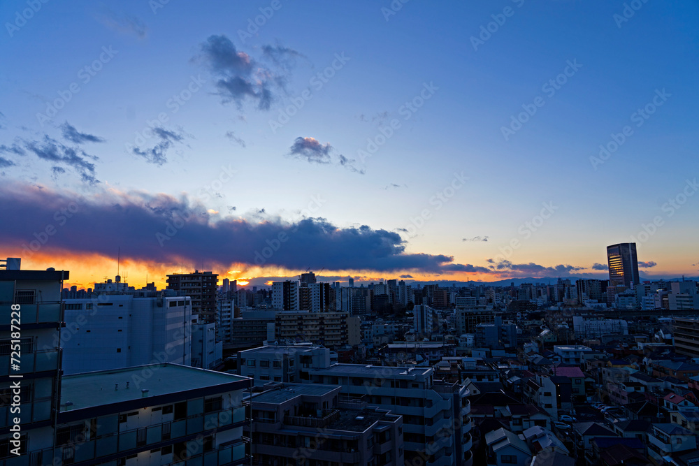 厚い雲と夕日と街並み