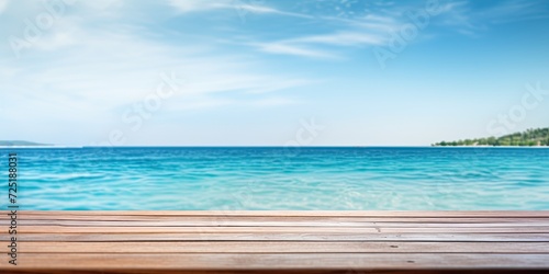 Blurred summer blue sea and sky background with wooden table top. © Lasvu