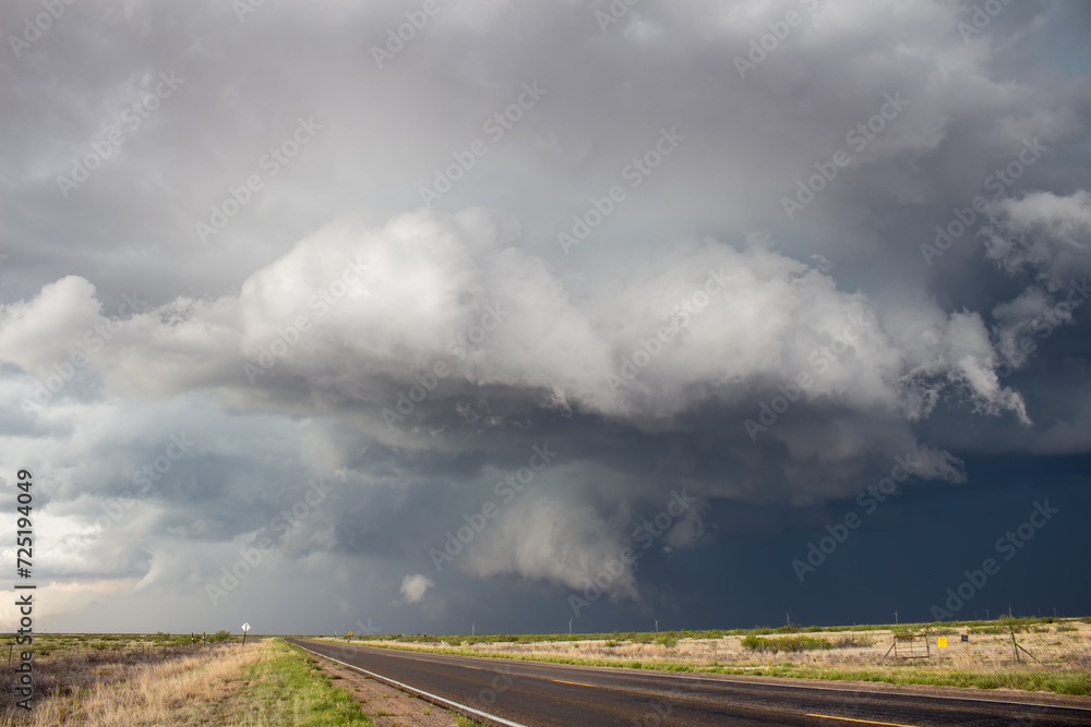A severe thunderstorm passes over an empty highway in the plains. A severe thunderstorm passes over an empty highway in the plains.