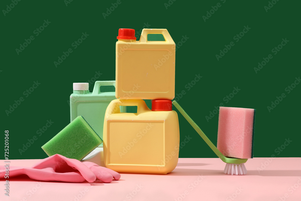 A set of different detergents, sponges, rubber gloves and brush decorated on a green background. Front view, scene for advertising with blank space for design A set of different detergents, sponges, rubber gloves and brush decorated on a green background. Front view, scene for advertising with blank space for design