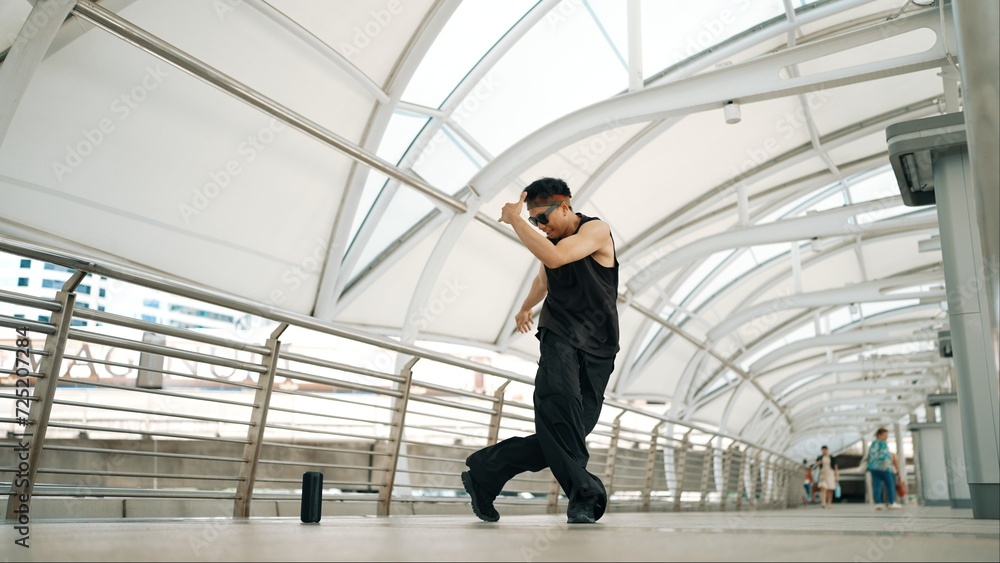 Skilled handsome hipster perform street dancing at narrow corridor. Professional hip hop dancer show b-boy step at corridor at urban city while wearing stylish cloth. Outdoor sport 2024. Sprightly.