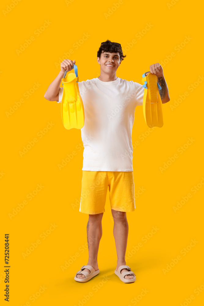 Young man with snorkeling mask and flippers on yellow background Young man with snorkeling mask and flippers on yellow background