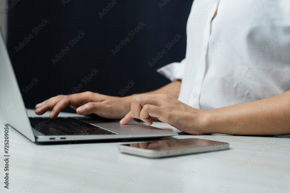Woman uses a smartphone or tablet in a dark room. Holding hands. Black background. Home office. For work. For social media or searching for information Woman uses a smartphone or tablet in a dark room. Holding hands. Black background. Home office. For work. For social media or searching for information