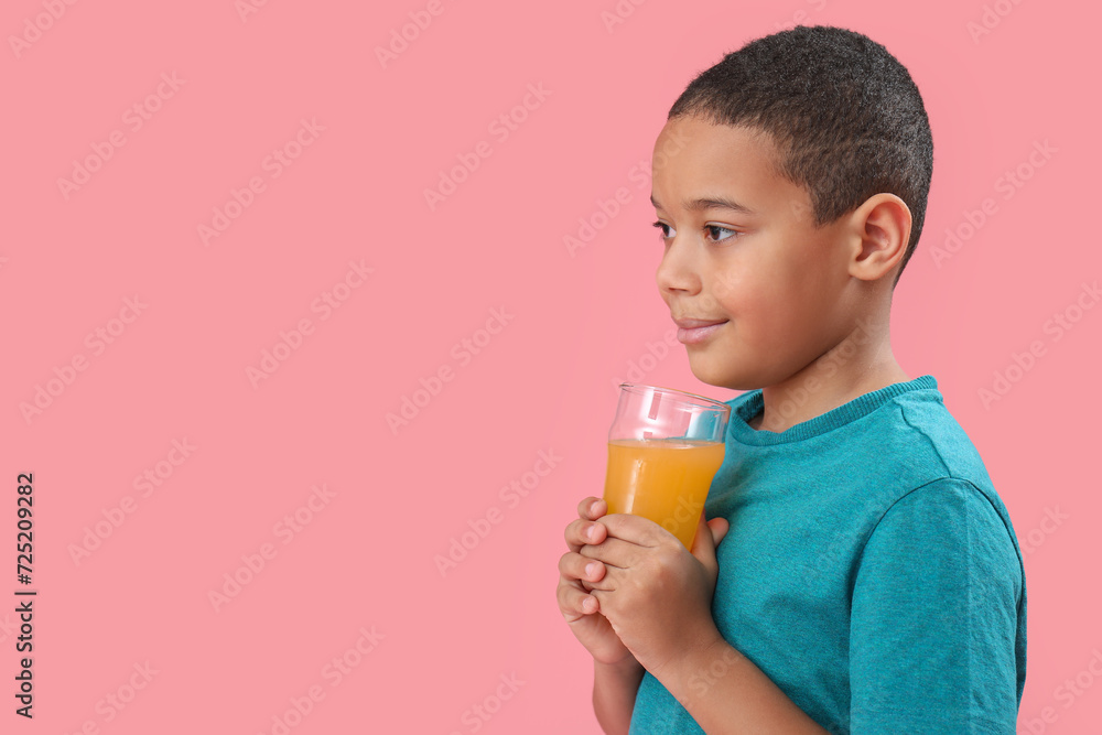 Little African-American boy with glass of orange juice on pink background Little African-American boy with glass of orange juice on pink background