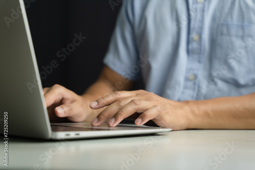 A man uses a smartphone or tablet in a dark room. Holding hands. Black background. Home office. For work. For social media or searching for information
