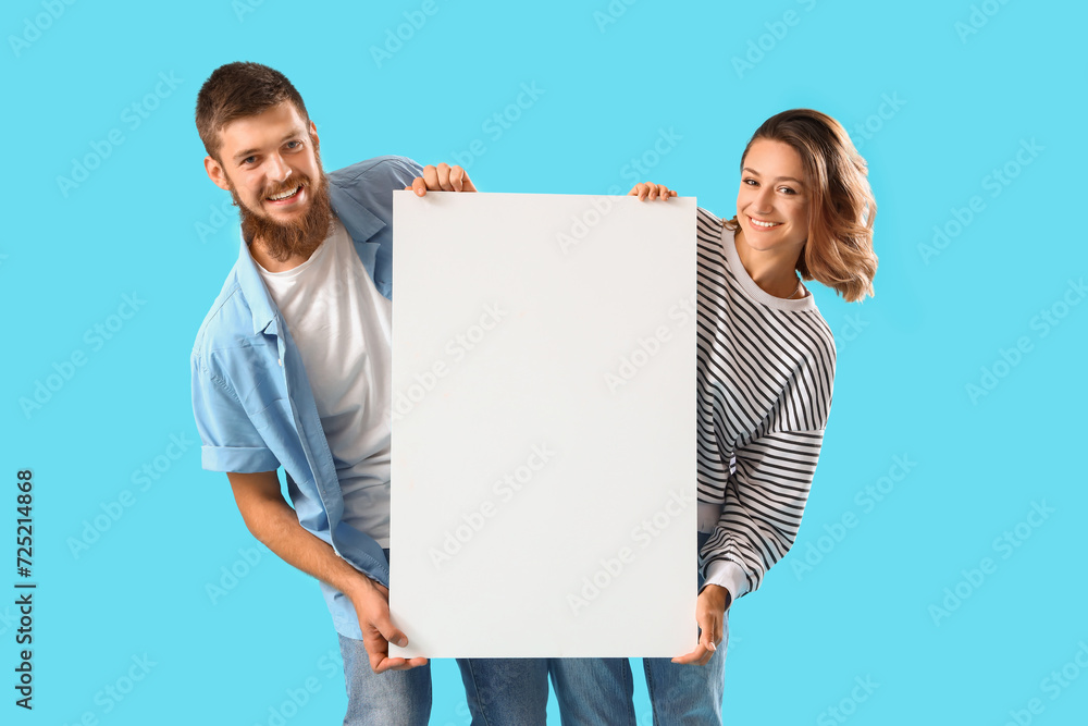Happy couple in love with blank poster on blue background Happy couple in love with blank poster on blue background