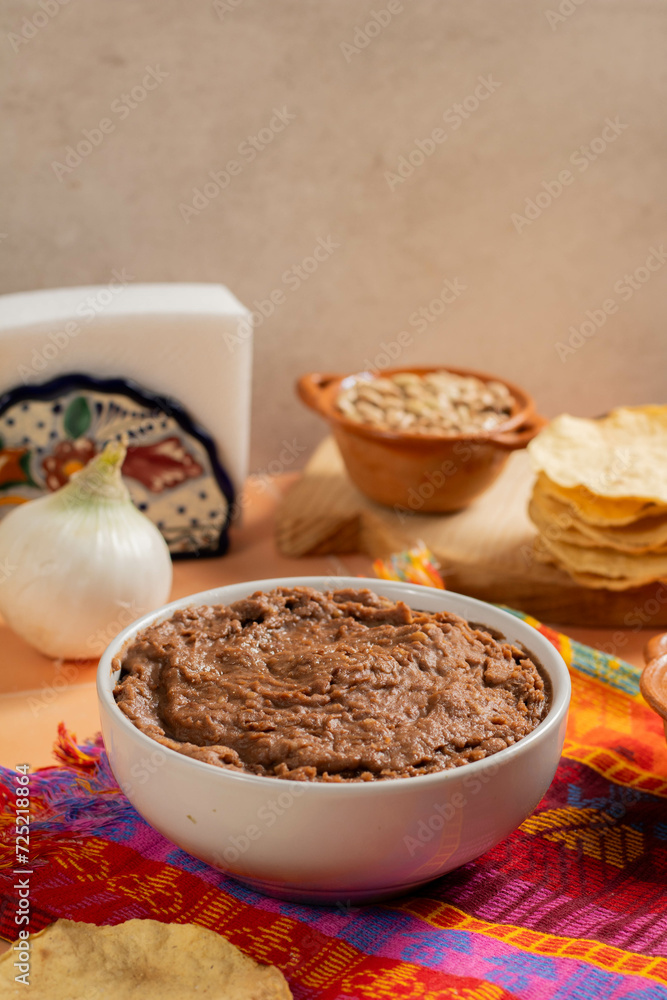 white plate full of refried bay beans, accompanied by cheeses and toast in Mexican cuisine white plate full of refried bay beans, accompanied by cheeses and toast in Mexican cuisine