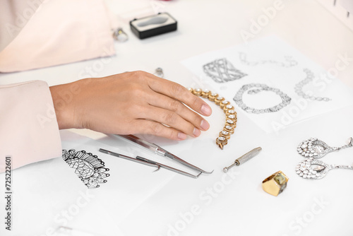 Female jewelry designer working with sketches of stylish accessories in office photo