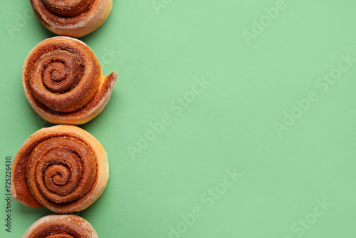 Tasty cinnamon rolls on green background