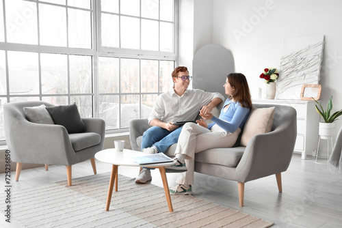 Young couple chatting on grey sofa in living room photo