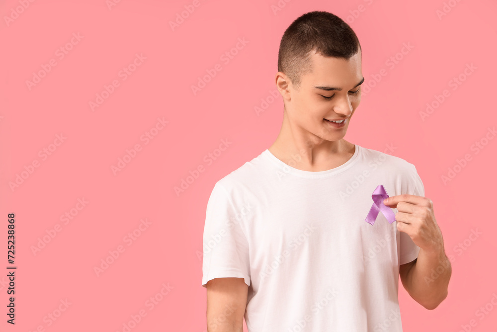 Young man with lavender awareness ribbon on pink background. World Cancer Day Young man with lavender awareness ribbon on pink background. World Cancer Day