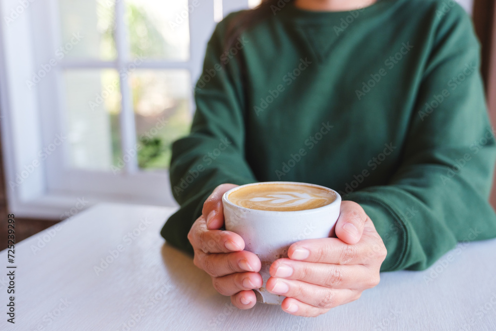 Closeup image of a woman holding a cup of latte coffee Closeup image of a woman holding a cup of latte coffee