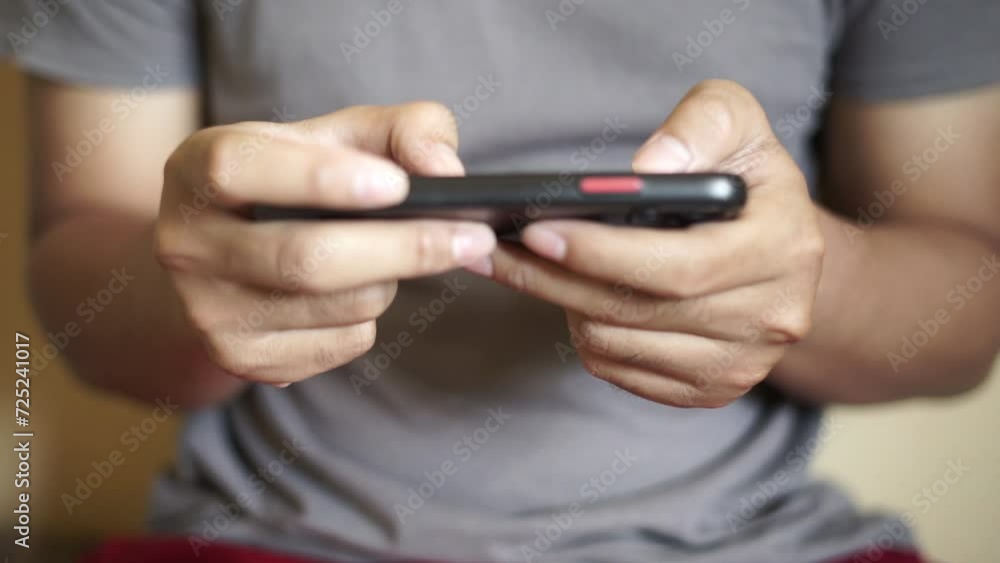 Hands of Asian man playing game on smartphone Hands of Asian man playing game on smartphone