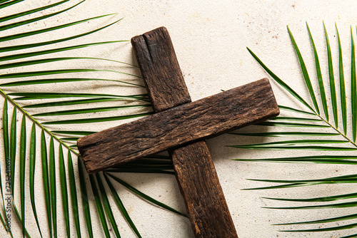 Wooden cross and palm leaves on white background