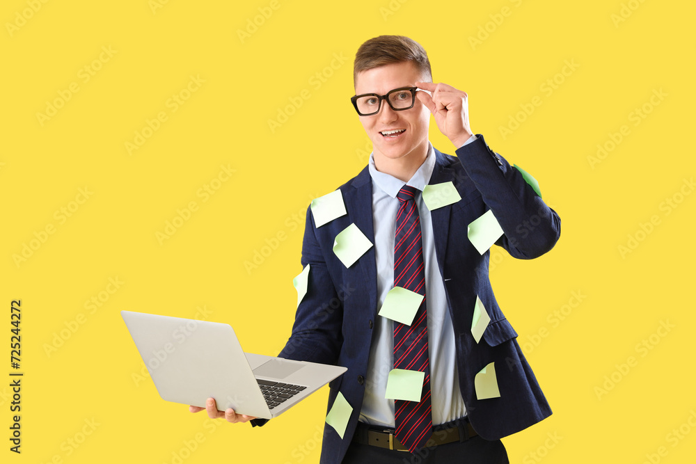 Funny businessman with sticky notes and laptop on yellow background Funny businessman with sticky notes and laptop on yellow background