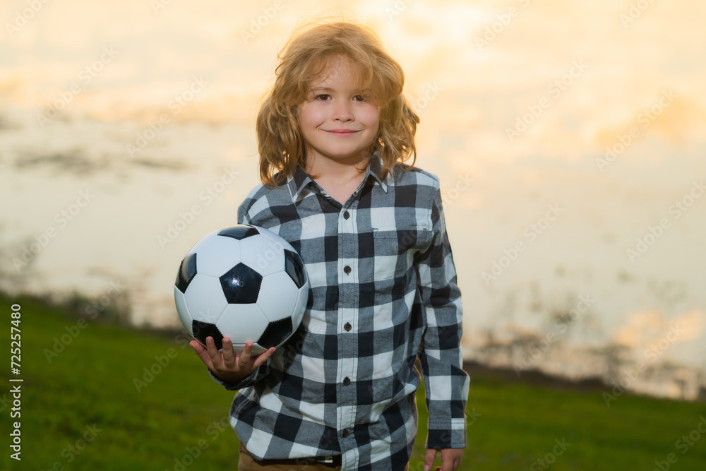 Child boy football or soccer player in action on soccer stadium kicking soccer ball for goal. Concept of sport, competition. Kid kick soccer ball. Kid kicking football ball. Sport for kids. Child boy football or soccer player in action on soccer stadium kicking soccer ball for goal. Concept of sport, competition. Kid kick soccer ball. Kid kicking football ball. Sport for kids.