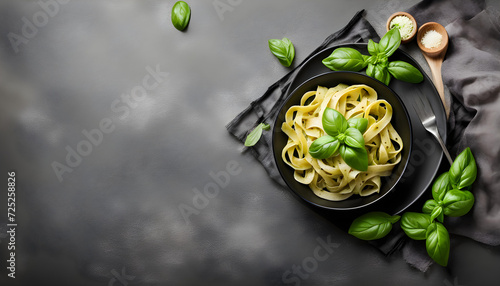 Pasta with pesto sauce and fresh basil leaves in black bowl.
