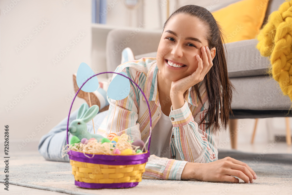 Young woman with basket of Easter eggs lying on floor at home Young woman with basket of Easter eggs lying on floor at home