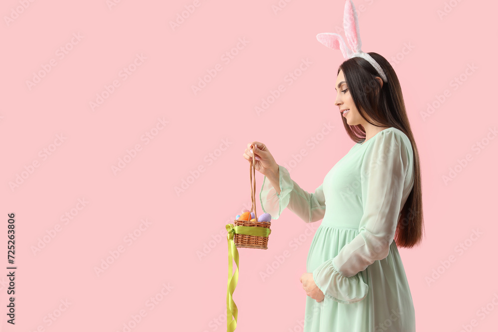 Young pregnant woman in bunny ears with Easter eggs on pink background Young pregnant woman in bunny ears with Easter eggs on pink background