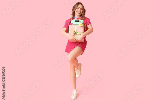Young woman with retro telephone, gift box and beautiful tulip on pink background. International Women's Day