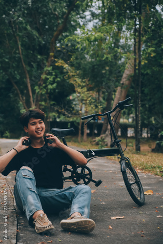 Young handsome bearded man taking a break while travelling the city with his bicycle using his digital tablet looking away thoughtfully