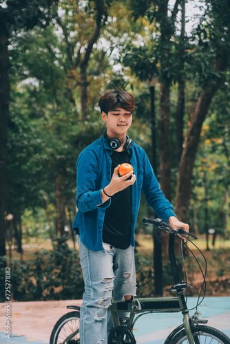 Young handsome bearded man taking a break while travelling the city with his bicycle using his digital tablet looking away thoughtfully