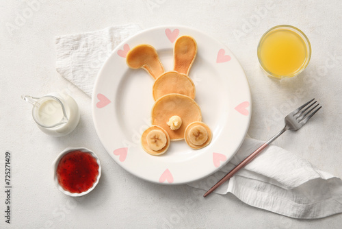 Funny Easter bunny pancakes with glass of orange juice on white background