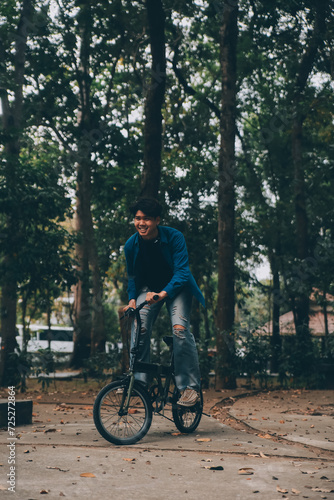 Young handsome bearded man taking a break while travelling the city with his bicycle using his digital tablet looking away thoughtfully