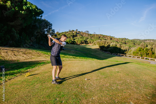 Sotogrante, Spain - January 25, 2024 - Man in mid-swing playing golf, trees and grassy field in background, sunny day.