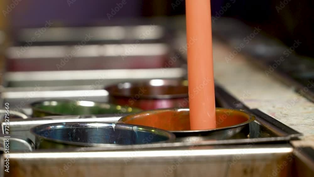 Handcrafted candles getting their color by dipping them in colorful candle wax Handcrafted candles getting their color by dipping them in colorful candle wax