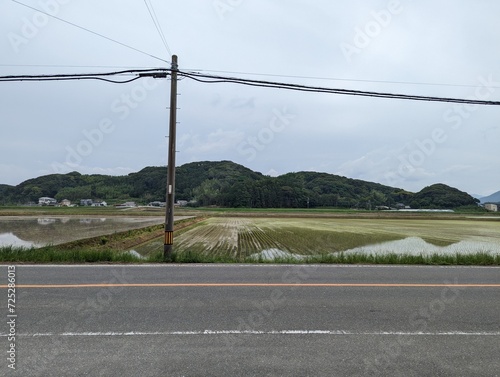  A tranquil rural landscape, with a road in the foreground and fields and hills in the background. 