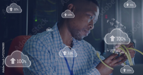 Image of cloud with uploading over african american man working in server room photo